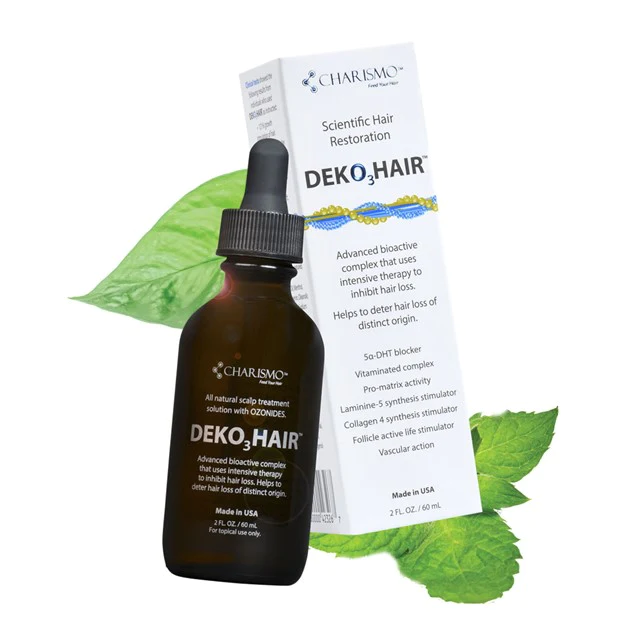 A bottle of hair oil next to some leaves