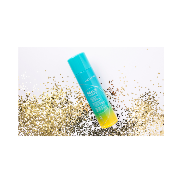 A blue and yellow tube of lip balm on top of some sand.