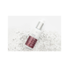 A bottle of serum sitting on top of some white sand.