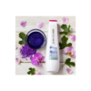 A bottle of hair conditioner and purple flower petals.